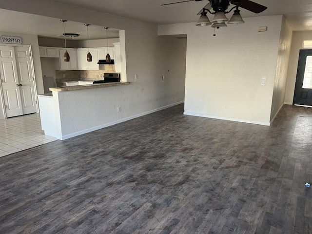 unfurnished living room featuring ceiling fan, baseboards, and dark wood-type flooring