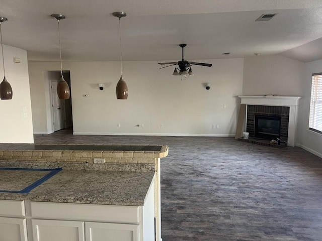 kitchen featuring visible vents, white cabinets, open floor plan, a brick fireplace, and dark wood finished floors