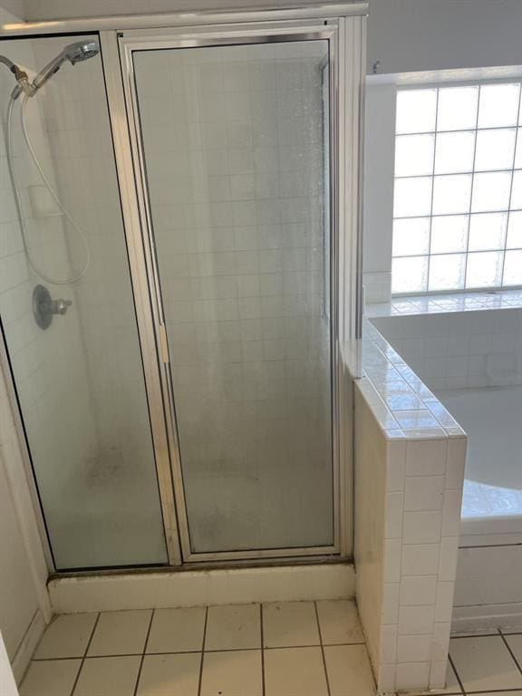 bathroom with tile patterned flooring, a garden tub, and a shower stall