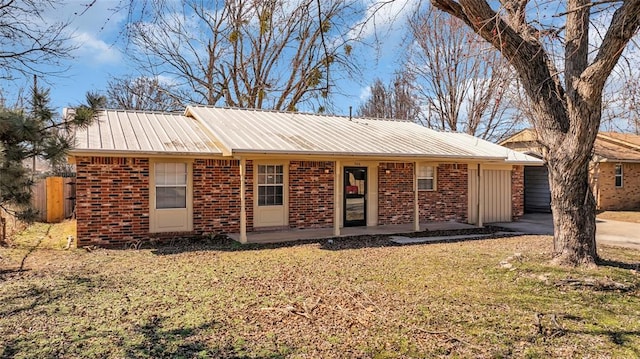 ranch-style home with a front yard, brick siding, and metal roof