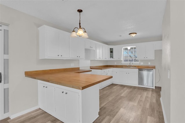 kitchen with a peninsula, a sink, white cabinets, stainless steel dishwasher, and light wood-type flooring