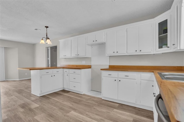 kitchen featuring a peninsula, light wood finished floors, wood counters, and white cabinetry