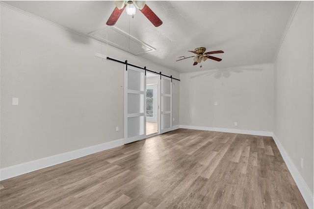 empty room featuring attic access, baseboards, ceiling fan, and wood finished floors