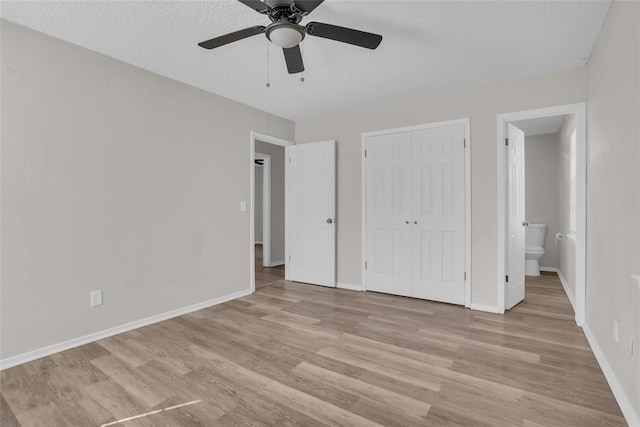 unfurnished bedroom with a closet, baseboards, a textured ceiling, and light wood finished floors