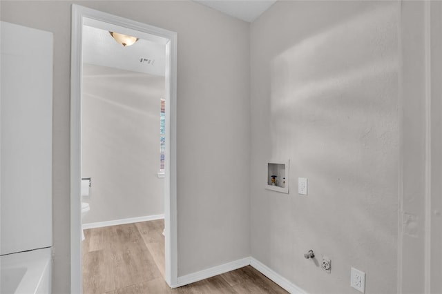 laundry area featuring gas dryer hookup, washer hookup, visible vents, baseboards, and light wood-type flooring