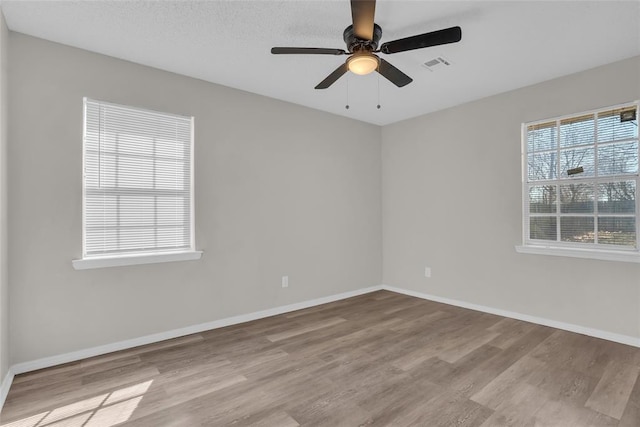 spare room featuring visible vents, baseboards, ceiling fan, and wood finished floors