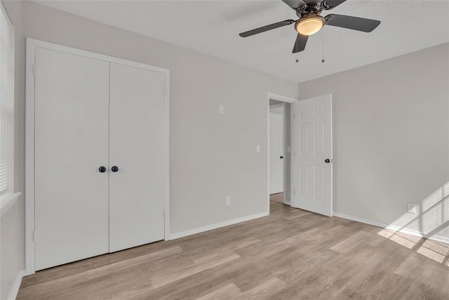 unfurnished bedroom featuring light wood-type flooring, a closet, ceiling fan, and baseboards