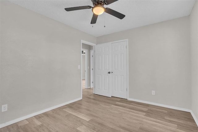 unfurnished bedroom featuring a ceiling fan, a closet, light wood-style flooring, and baseboards