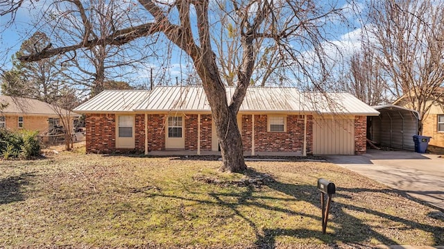 ranch-style home with driveway, a detached carport, metal roof, and brick siding