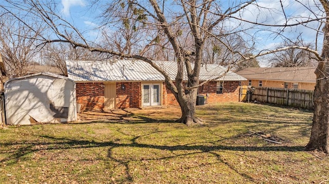 exterior space featuring cooling unit, brick siding, an outdoor structure, fence, and a lawn