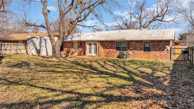 rear view of house with fence, a lawn, and brick siding