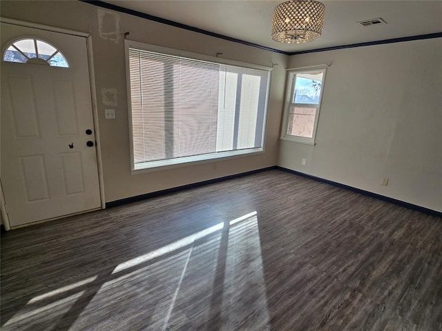 foyer entrance with visible vents, crown molding, baseboards, and wood finished floors