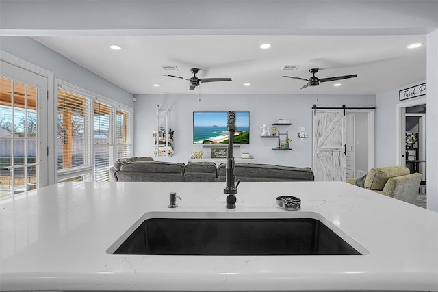 kitchen featuring light stone countertops, open floor plan, a sink, and a barn door