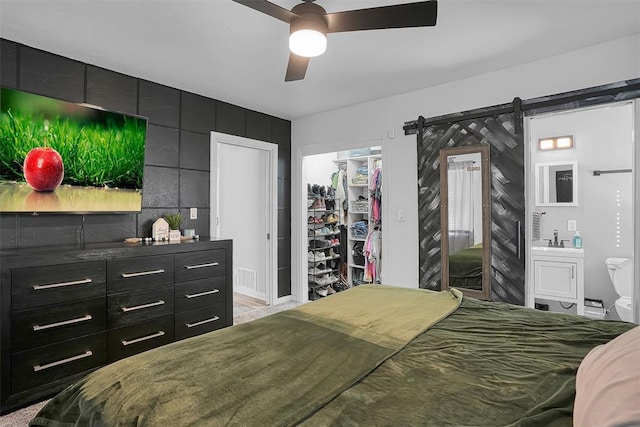 bedroom featuring a closet, visible vents, a spacious closet, a barn door, and a ceiling fan