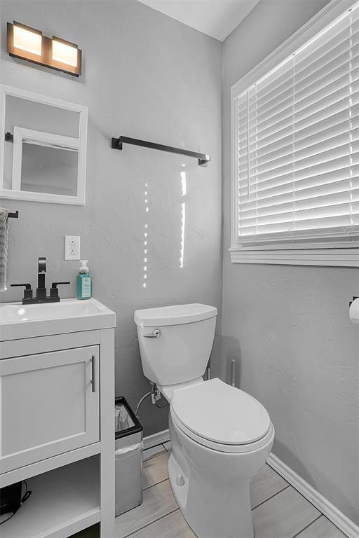 half bathroom featuring baseboards, vanity, and toilet