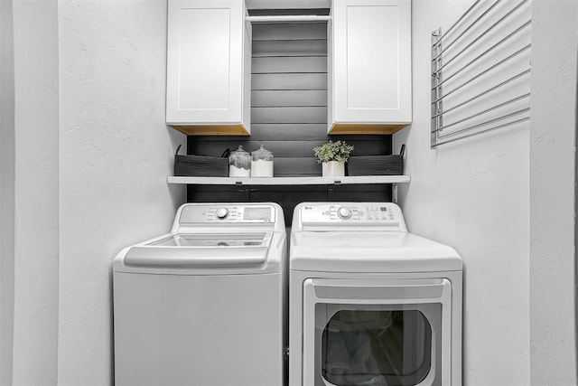 laundry area with cabinet space, a textured wall, and washing machine and clothes dryer