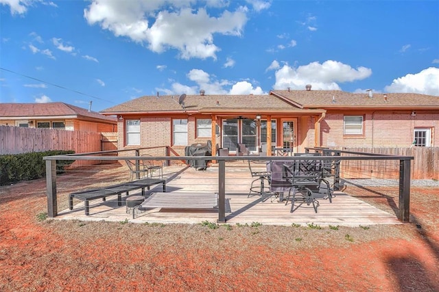 back of property featuring brick siding, fence, and a wooden deck