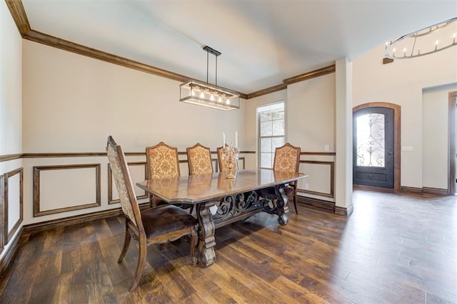 dining space with baseboards, arched walkways, ornamental molding, wood finished floors, and an inviting chandelier