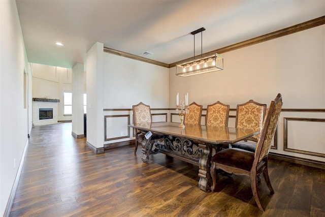 dining room with ornamental molding, visible vents, a fireplace, and wood finished floors