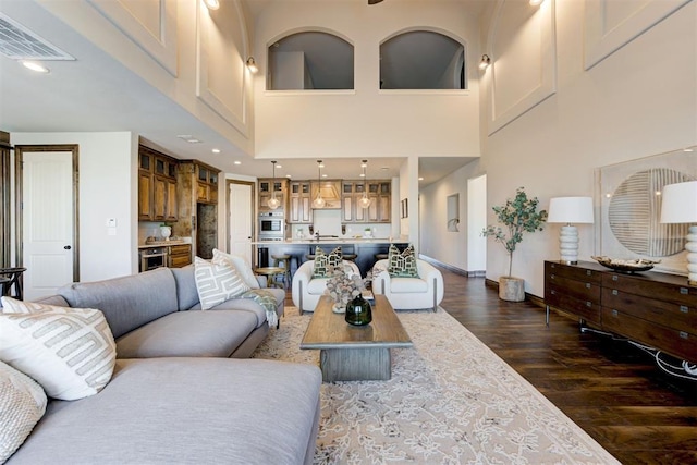 living room featuring recessed lighting, a high ceiling, dark wood-style flooring, visible vents, and baseboards