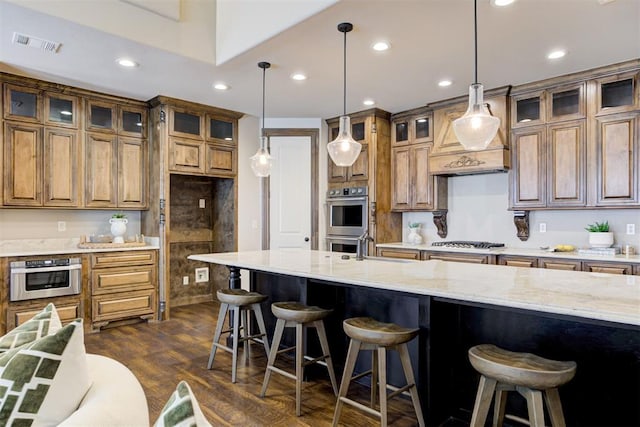 kitchen featuring visible vents, brown cabinets, dark wood-type flooring, light stone countertops, and stainless steel appliances