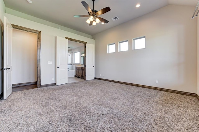 unfurnished bedroom featuring visible vents, baseboards, ensuite bath, vaulted ceiling, and carpet flooring