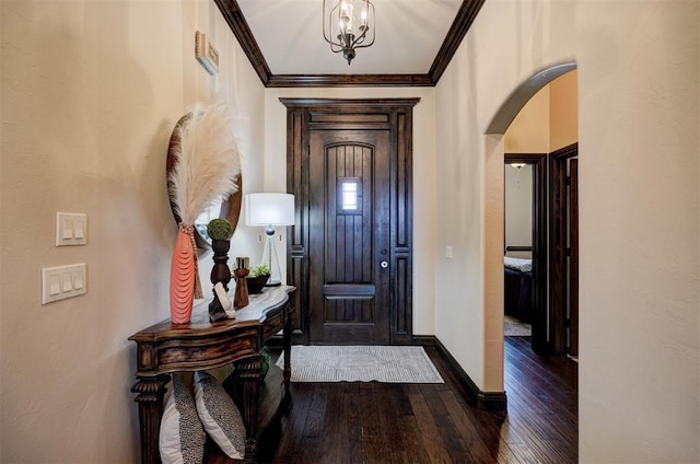 entryway featuring baseboards, hardwood / wood-style floors, ornamental molding, arched walkways, and a notable chandelier