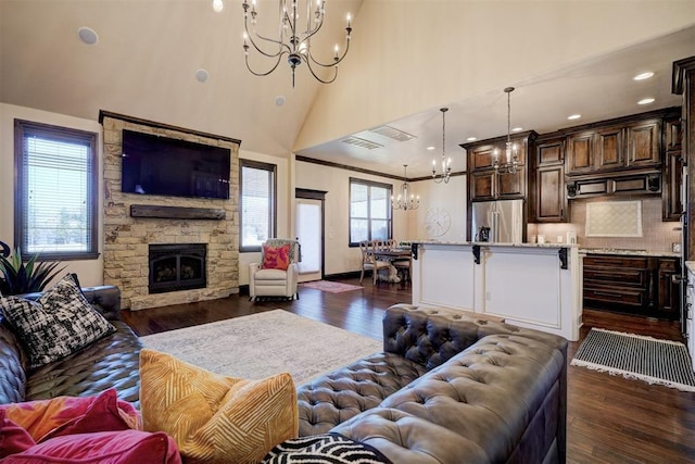 living area featuring a notable chandelier, a stone fireplace, and dark wood-style flooring