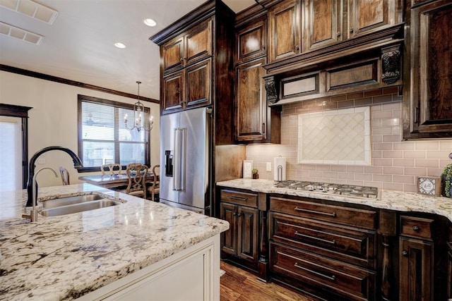 kitchen with a sink, ornamental molding, light stone countertops, and stainless steel appliances