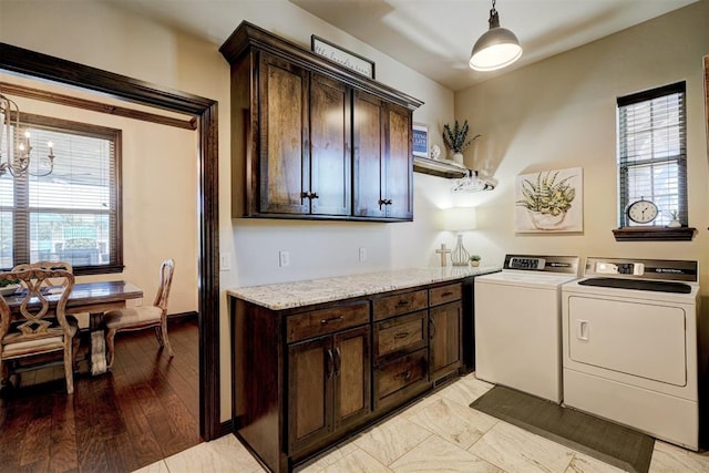 washroom with a notable chandelier, cabinet space, light wood-style floors, and washing machine and clothes dryer