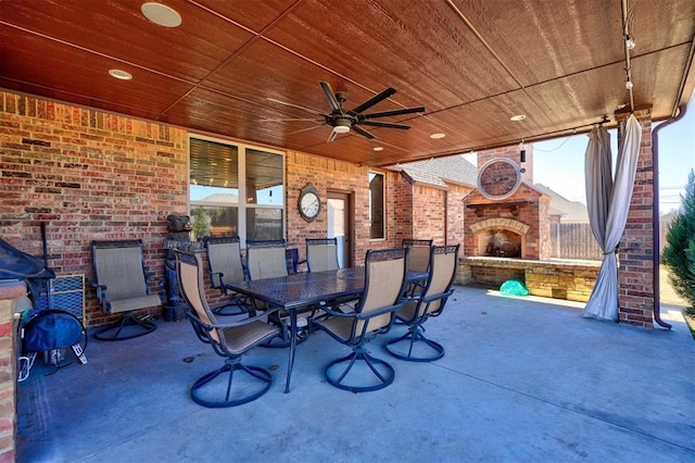 view of patio featuring outdoor dining space, ceiling fan, and an outdoor brick fireplace