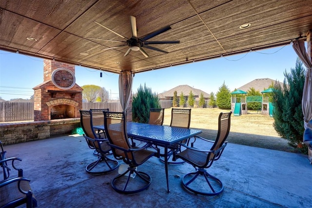 view of patio with ceiling fan, outdoor dining area, an outdoor brick fireplace, and fence