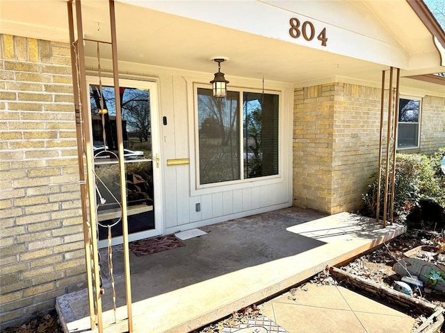 property entrance featuring board and batten siding and brick siding