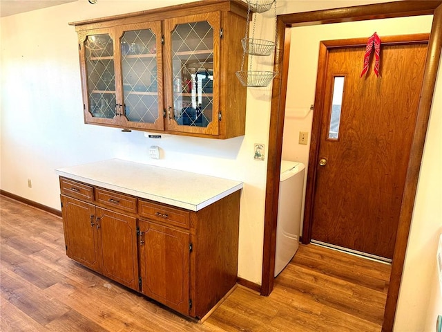 kitchen with light countertops, glass insert cabinets, light wood-style flooring, and baseboards