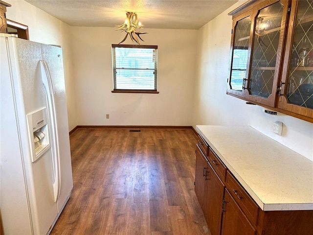 kitchen featuring glass insert cabinets, a wealth of natural light, white refrigerator with ice dispenser, and dark wood finished floors