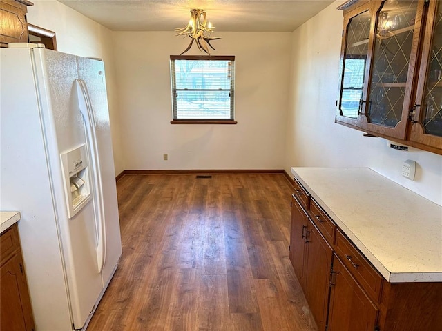 kitchen featuring dark wood-style floors, white fridge with ice dispenser, light countertops, and baseboards