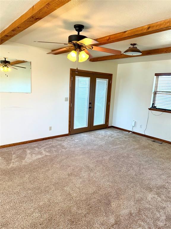 unfurnished room with light carpet, french doors, beam ceiling, and baseboards