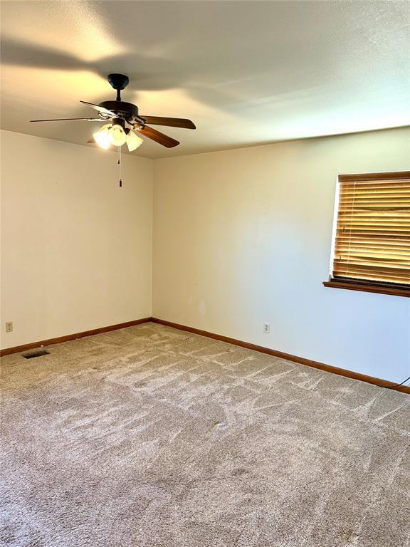 carpeted spare room with baseboards, visible vents, ceiling fan, and a textured ceiling