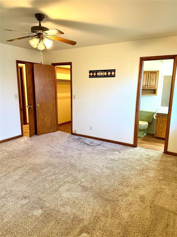 unfurnished bedroom with carpet, a closet, baseboards, and ensuite bathroom