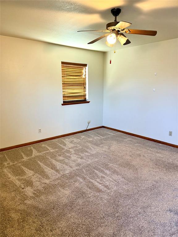 spare room featuring a ceiling fan, baseboards, and carpet flooring