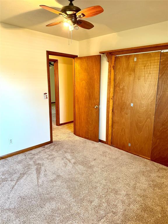 unfurnished bedroom with carpet flooring, a ceiling fan, and baseboards