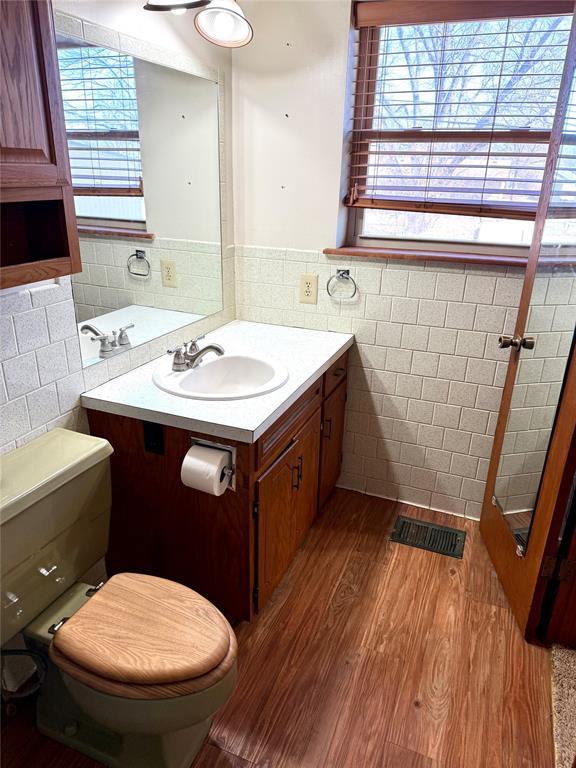 bathroom with visible vents, tile walls, toilet, and wood finished floors