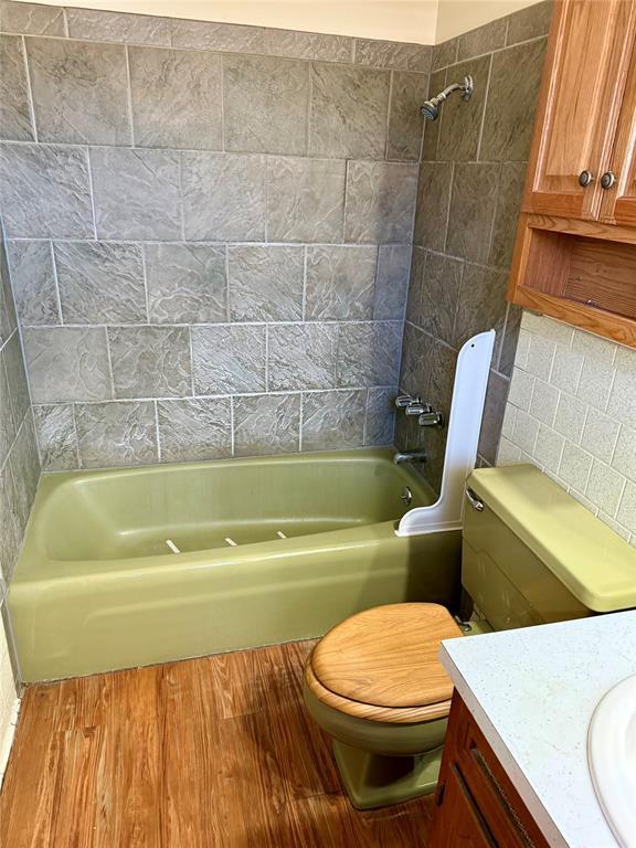 bathroom featuring toilet, tub / shower combination, wood finished floors, and vanity