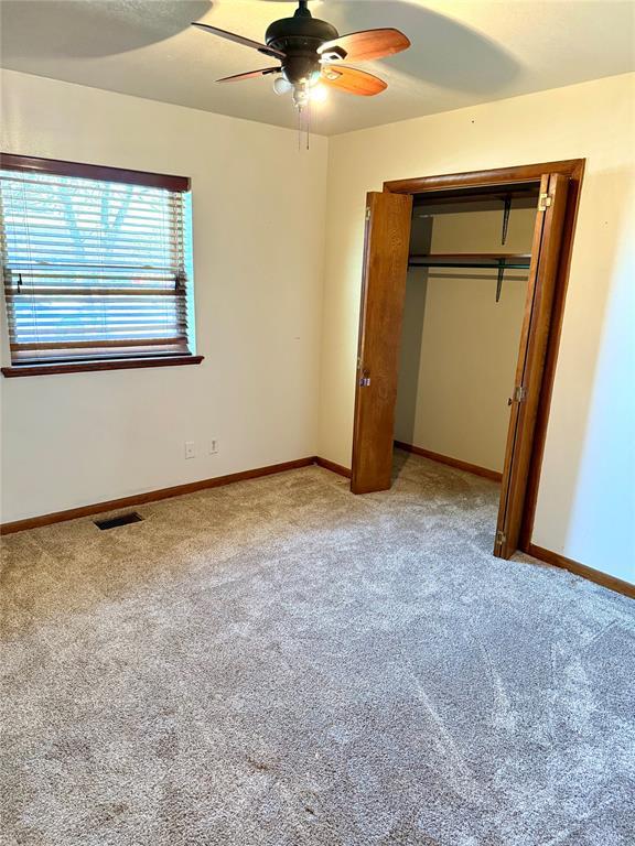 unfurnished bedroom with baseboards, visible vents, a closet, and light colored carpet