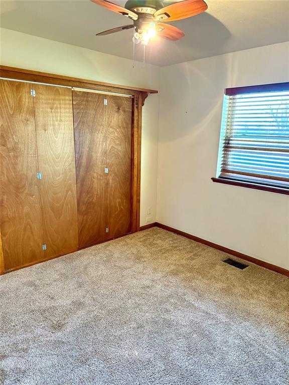 unfurnished bedroom with carpet floors, a ceiling fan, visible vents, and baseboards