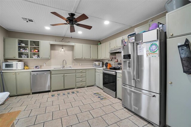 kitchen featuring a ceiling fan, a sink, stainless steel appliances, light countertops, and green cabinetry