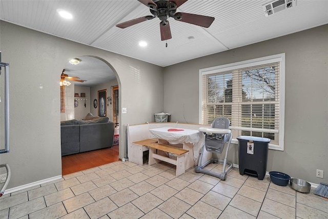 dining space featuring visible vents, baseboards, light tile patterned floors, arched walkways, and a ceiling fan