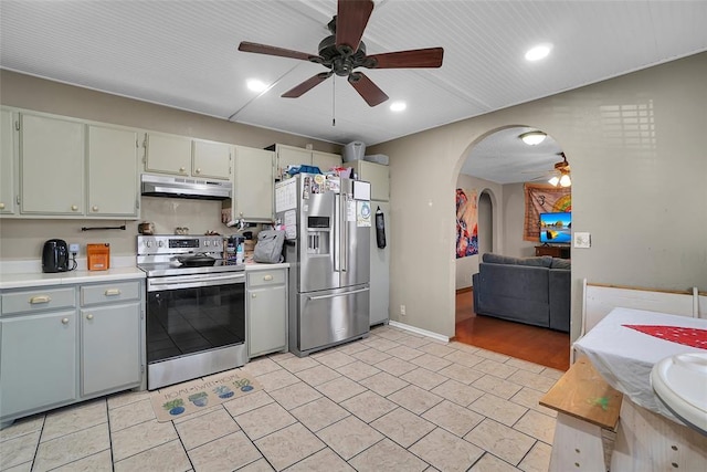 kitchen featuring under cabinet range hood, light countertops, appliances with stainless steel finishes, arched walkways, and a ceiling fan