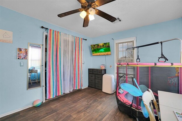 game room with a textured ceiling, wood finished floors, visible vents, and ceiling fan