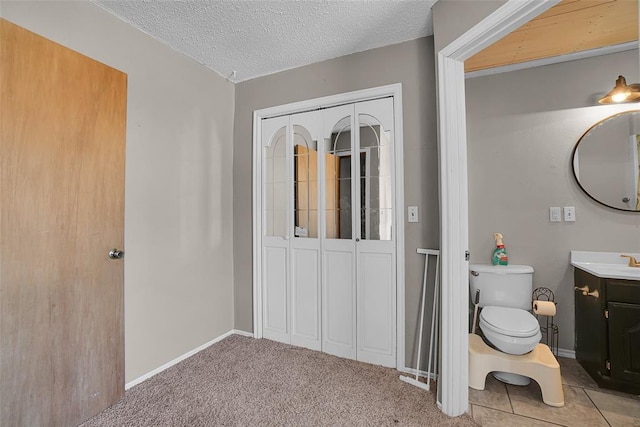 bathroom featuring baseboards, a textured ceiling, vanity, and toilet